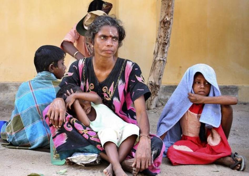 Eine Mutter sitzt mit ihren Kindern an einer Hauswand in Sri Lanka
